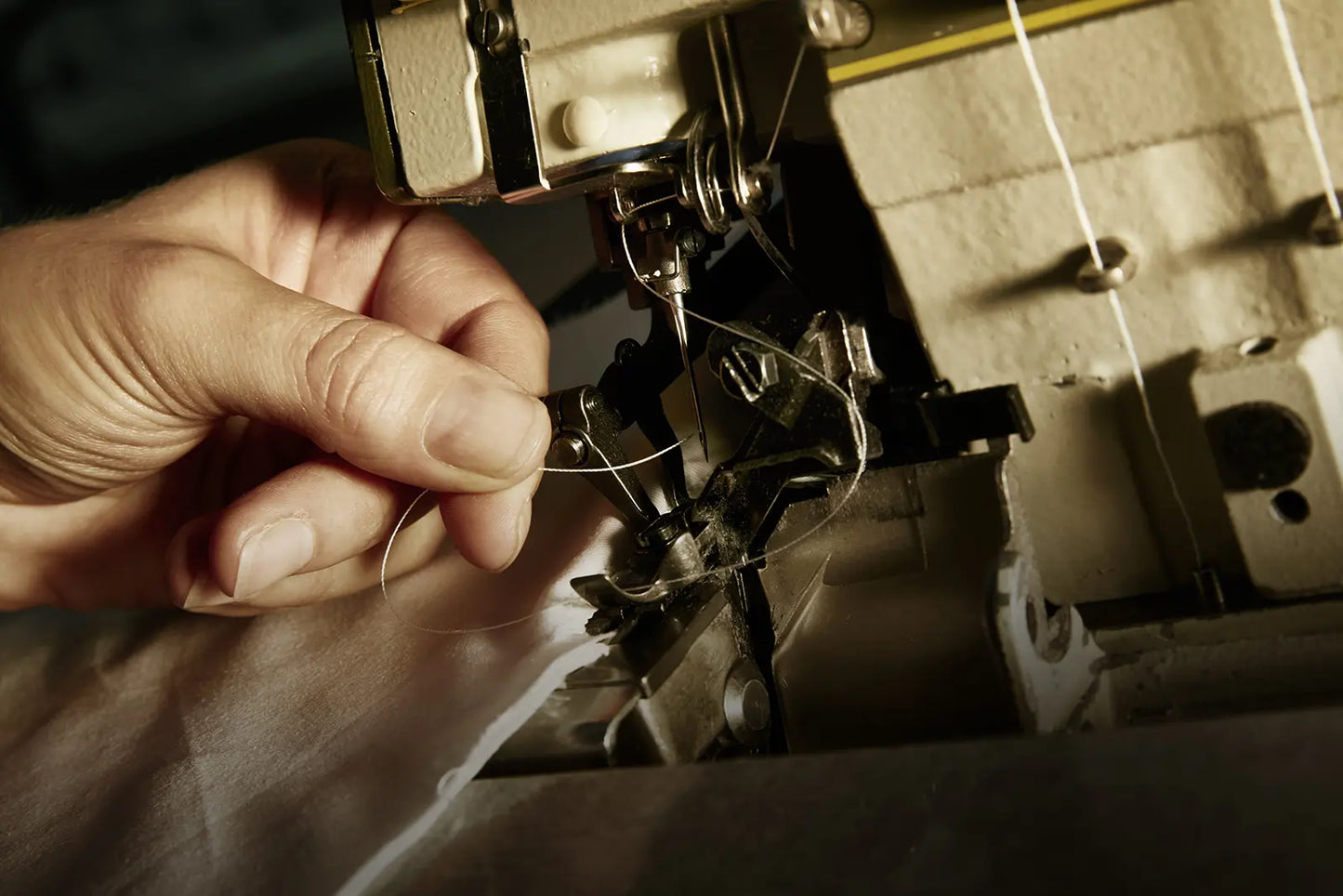Main qui passe un fil de couture dans une aiguille